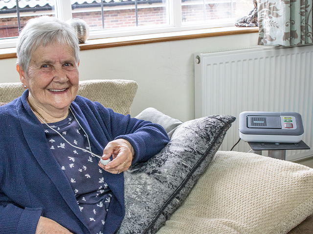 Lady pressing her MyAmie personal alarm to link with her Lifeline alarm